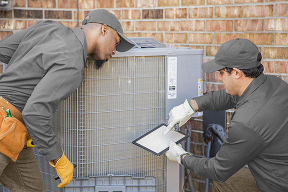 Two techs performing maintenance on an outdoor AC unit