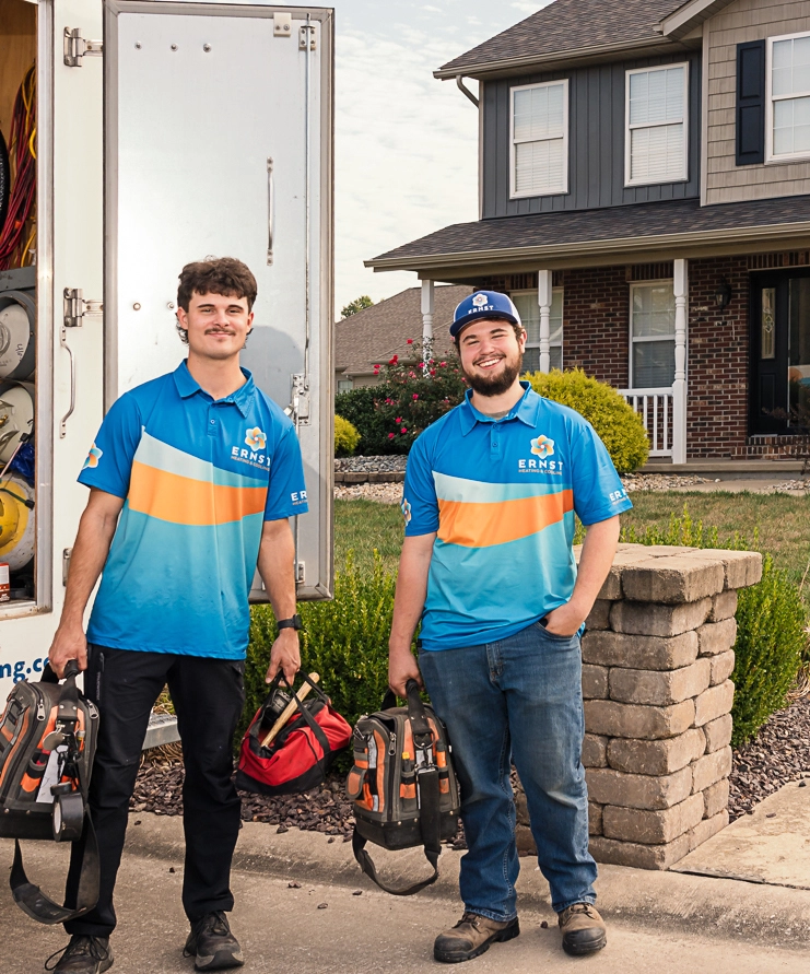 Ernst Heating and Cooling technicians smiling outside their truck